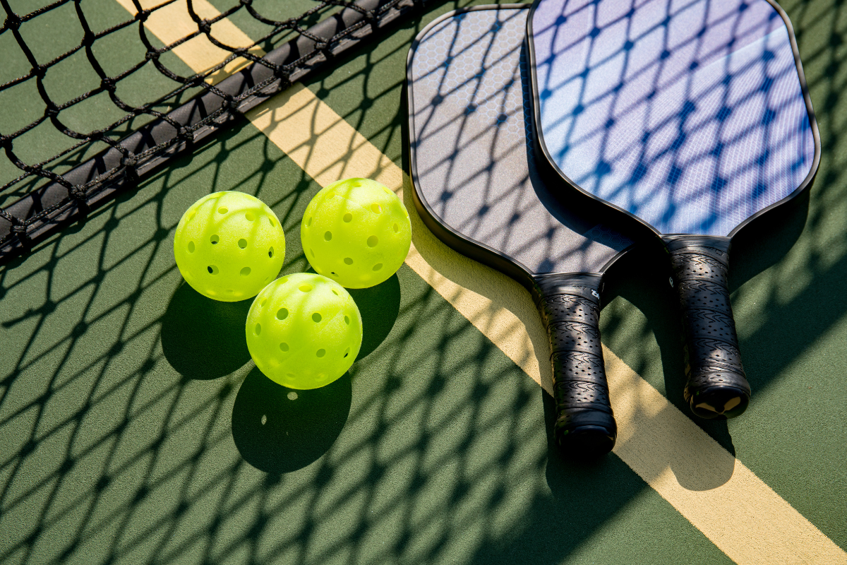 pickleball paddle and pickleballs in pickleball court